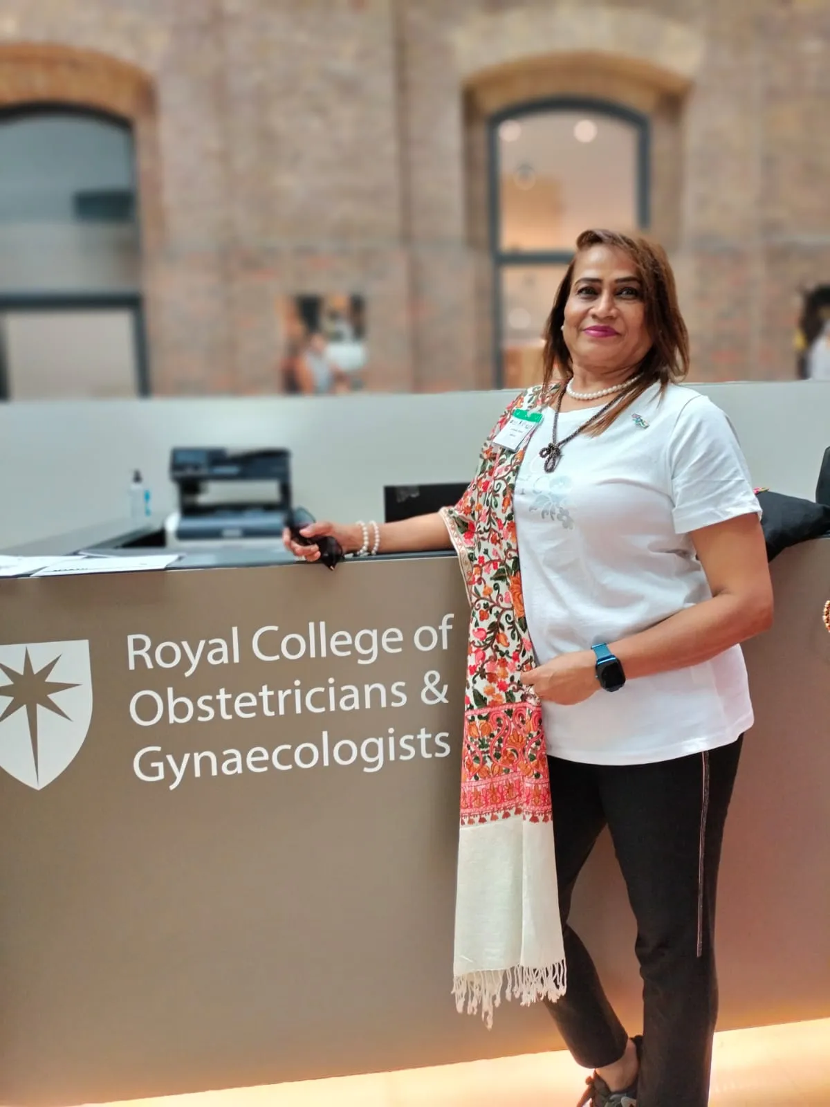 Dr. Fehmida Shaikh at the Royal College of Obstetricians & Gynaecologists emblem wall, London