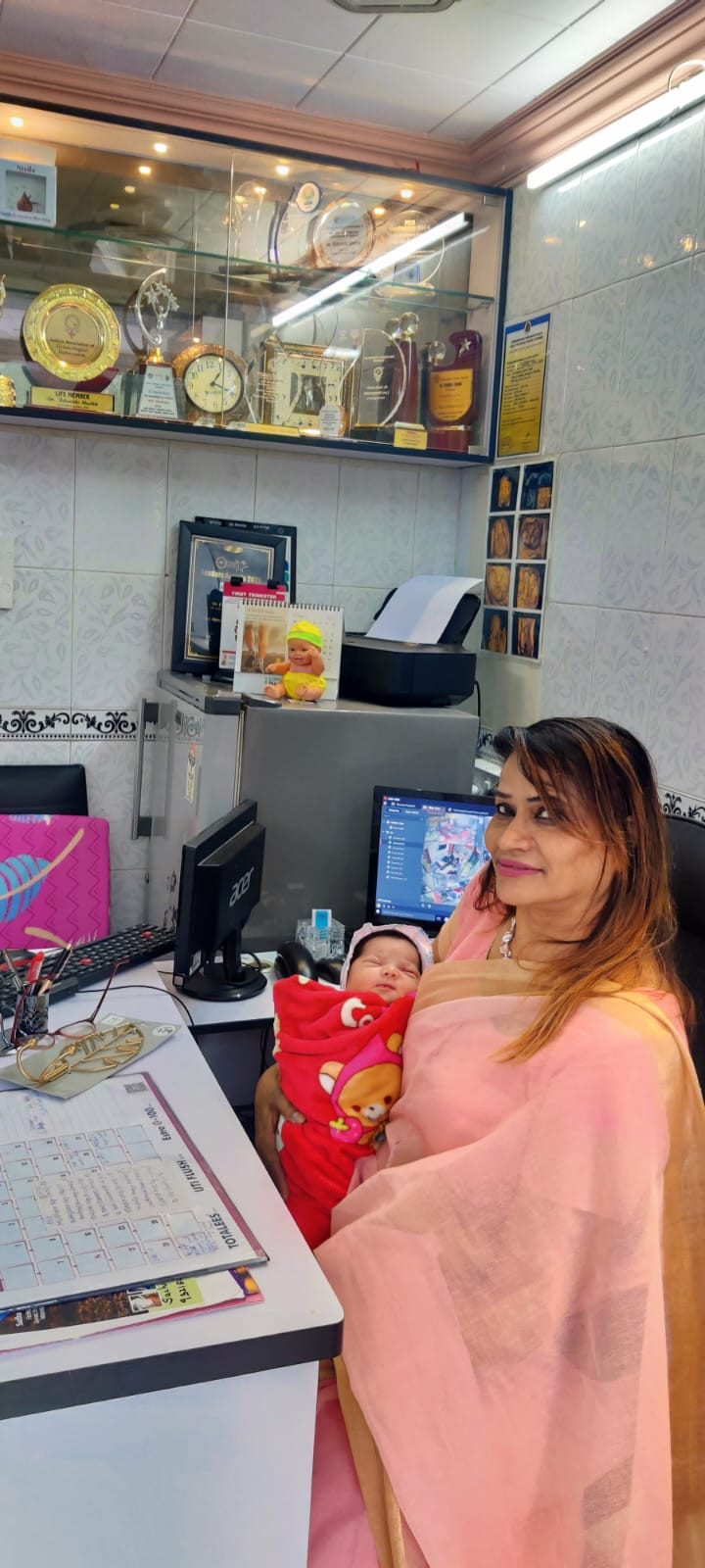 Dr. Fehmida Shaikh cradling a newborn at the clinical ultrasound desk